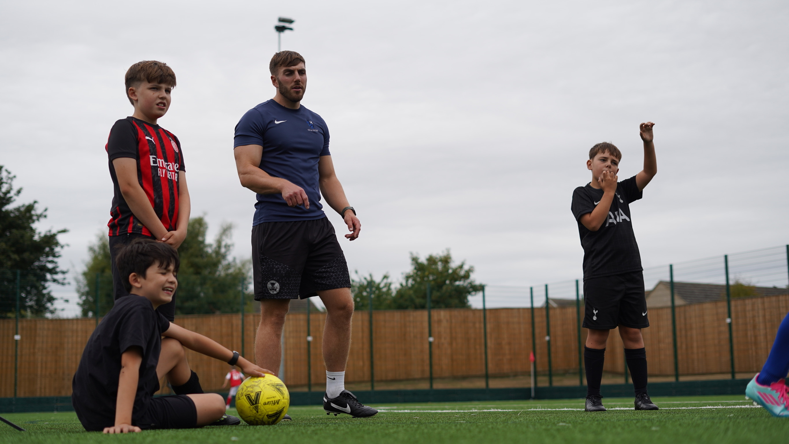Tom Russell coaching a small group of players on a local 3G pitch